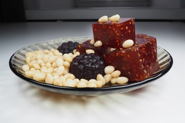 pieces of natural marmalade and pine nuts in a glass plate