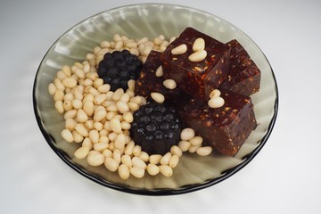 pieces of natural marmalade and pine nuts in a glass plate