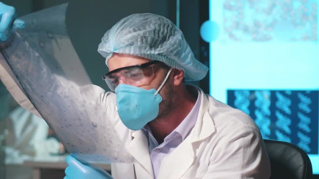 Professor in mask examines a snapshot of a cell