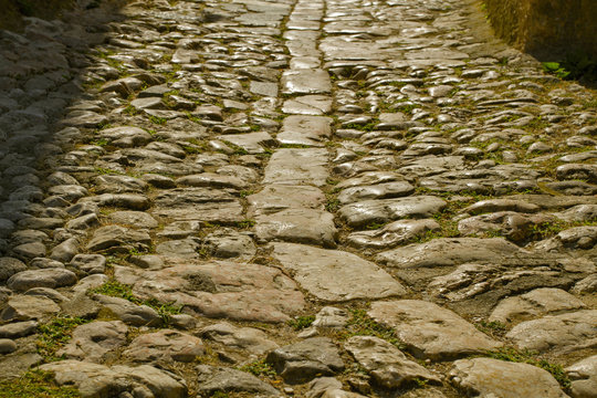 Fototapeta Ancient road paved with cobblestone . Road in a historical place. Cobblestone pavement texture.