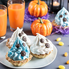 Halloween sweet treats, party food concept. White and blue cakes with faces close up.