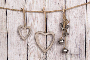 Corazones de madera y cascabeles colgados sobre fondo de madera.