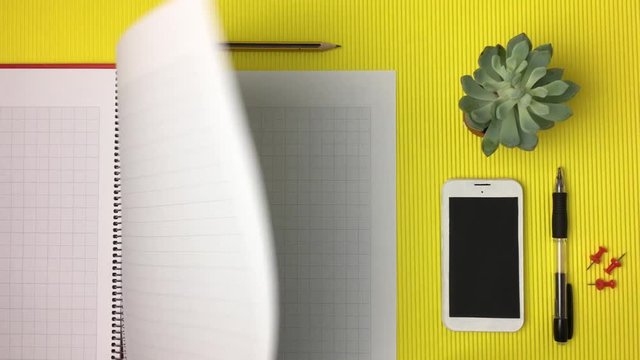 Libreta pasando paginas sobre fondo amarillo.