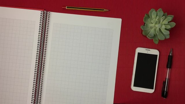 Escena de una libreta en la que pasan las paginas, sobre fondo rojo.