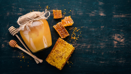 Honey in a jar on a black wooden background. Free space for text. Top view.