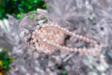 selective focus of natural pearl necklace in wine glass, holiday season background.