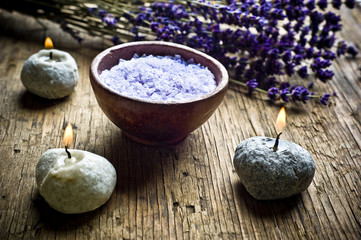 Fototapeta na wymiar wellness spa concept with bowl of salt, three candles and dry lavender