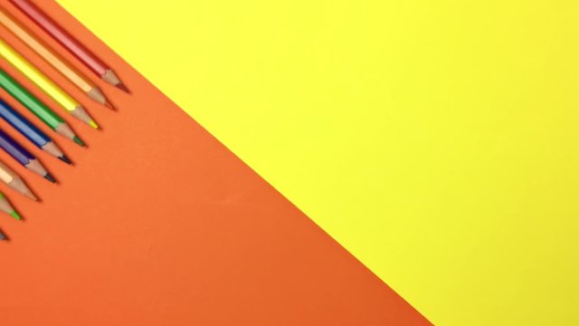 Sobre fondo naranja y amarillo aparecen lapices de colores.