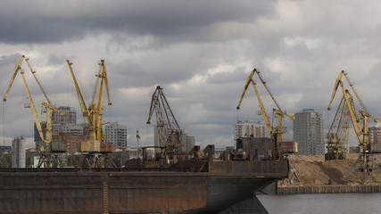 Fototapeta na wymiar A barge on the river and cranes on the background. Format 16:9