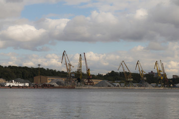 View of the pier on the river with cranes, sand, gravel. Industrial landscape