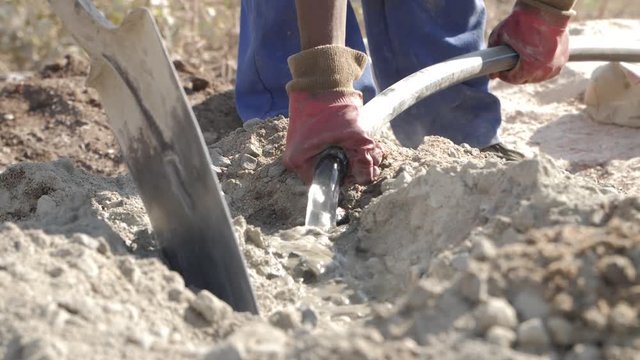 African construction working mixing concrete in blue overalls - Two Shots - 4K Slowmotion.