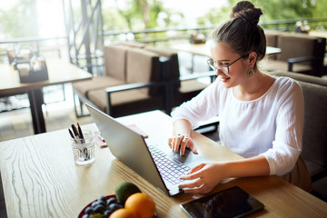 Young mixed race woman working with laptop in cafe at tropical location. Asian caucasian female studying using internet. Business woman doing social marketing work and shopping. Telecommuting concept.