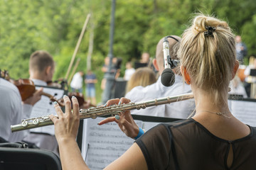 Girl playing the flute in the park. woman playing flute. game on a musical instrument flute at event. flute is close-up © jollier_