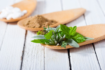 lavender, thyme, mint and sage herbal leaves on bamboo spoon, white wooden table background