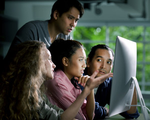 Group of young businesspersons looking intently at the screen with shock anxious and worried expression