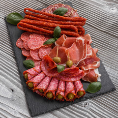 Cold smoked meat plate on a rustic wooden background