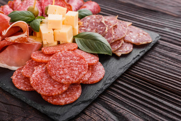 Cold smoked meat plate on a rustic wooden background