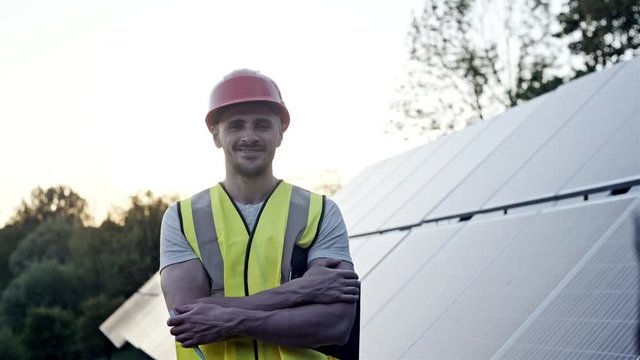 The portrait of a proud young engineer smiles satisfied with his successful work with his arms crossed. Concept: renewable energy, technology, electricity, service, green power.