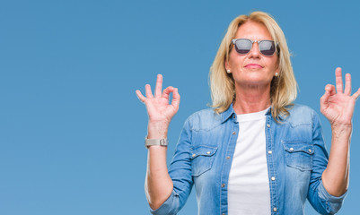Middle age blonde woman wearing sunglasses over isolated background relax and smiling with eyes closed doing meditation gesture with fingers. Yoga concept.