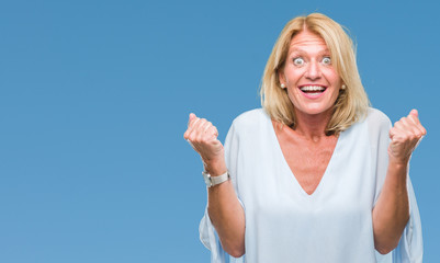 Fototapeta premium Middle age blonde business woman over isolated background celebrating surprised and amazed for success with arms raised and open eyes. Winner concept.