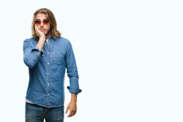 Young handsome man with long hair wearing sunglasses over isolated background thinking looking tired and bored with depression problems with crossed arms.