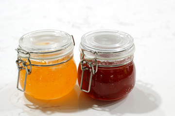 homemade strawberry and pineapple jam in jars on white table