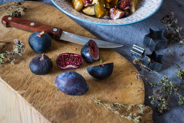 Black ripe raw figs halves cut on wooden board. Subtropical, tropical fruits. Diet breakfast. Vitamins and minerals