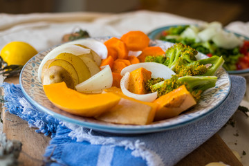 Steamed cooked assorted vegetables. Carrots, pumpkin, roasted potato, onion rings, broccoli. Seasonal vegan lunch, vegetarian autumn dinner, healthy food. With herbs, spices.