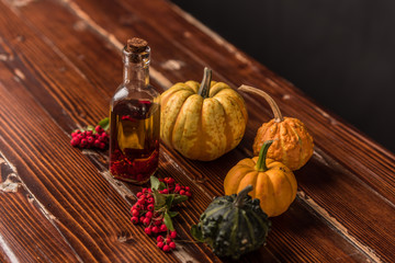 homemade olive oil with chilli pepper surrounded by pumpkins, leaves and rowan
