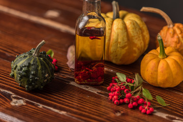 homemade olive oil with chilli pepper surrounded by pumpkins, leaves and rowan