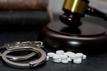 Judge's gavel with handcuffs, drugs on wooden table, drugs concept