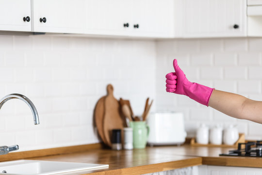 Woman hands wearing protective gloves on white kitchen background. Concept of clean kitchen, successful thumb up yes ok sign