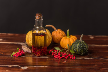Obraz na płótnie Canvas homemade olive oil with chilli pepper surrounded by pumpkins, leaves and rowan