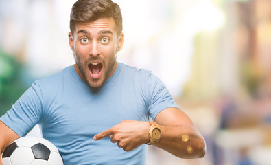 Young handsome man holding soccer football ball over isolated background very happy pointing with hand and finger