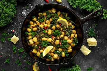 Fried kale and potato gnocci with chilie, peccorino cheese and lemon wedges in rustic pan. Italian food