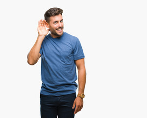 Young handsome man over isolated background smiling with hand over ear listening an hearing to rumor or gossip. Deafness concept.