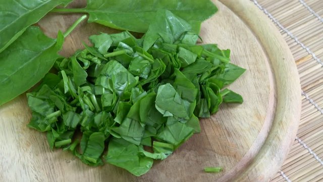 Rotating fresh cut healthy food spinach on wooden cutting board

