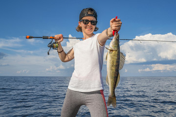 Happy fisher girl with walleye zander fish trophy at the boat