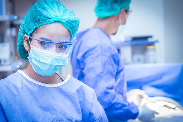 Portrait of female surgeon , operation in the background.
