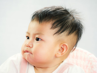 Portrait of cute short hair asia baby girl frowned and look something on white background