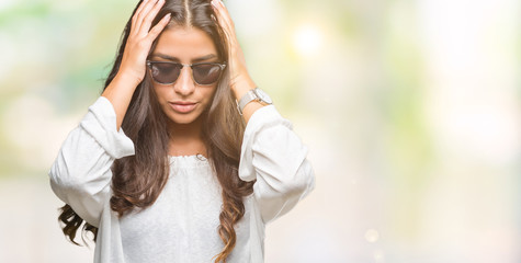 Young beautiful arab woman wearing sunglasses over isolated background suffering from headache desperate and stressed because pain and migraine. Hands on head.