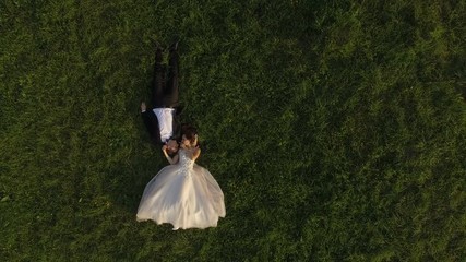 Top view of wedding couple lying on green grass and resting - Powered by Adobe