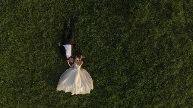 Top view of wedding couple lying on green grass and resting