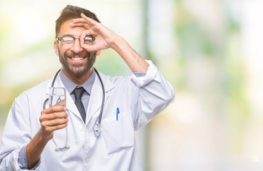 Adult hispanic doctor man drinking glass of water over isolated background with happy face smiling doing ok sign with hand on eye looking through fingers