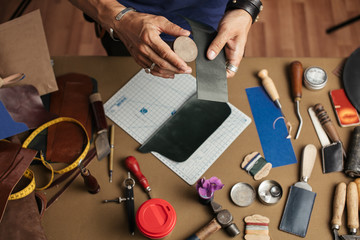 Working process of hand made leather wallet production in the leather workshop. Male hands close up...