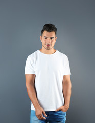Obraz premium Young man in t-shirt on grey background. Mockup for design