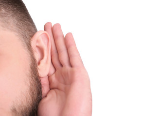 Young man with hearing problem on white background, closeup