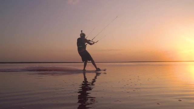 A beautiful sunset on the lake, a man in a helmet is engaged in kitesurfing