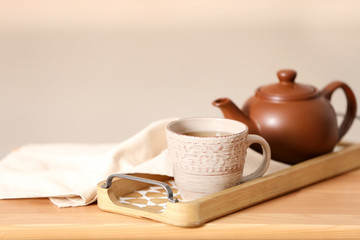 Tray with tea set on table against light background