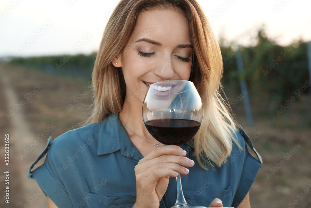 Wall mural Young beautiful woman enjoying wine at vineyard